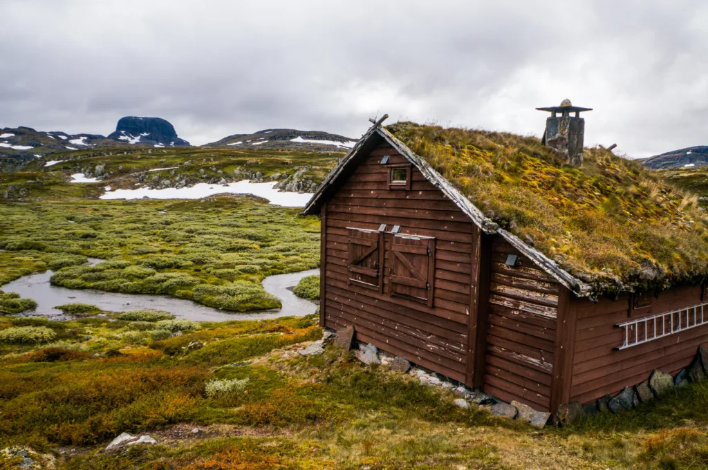 beau paysage avec petite maison sur une prairie avec montagnes et rivière, Norvège, Hardangervidda