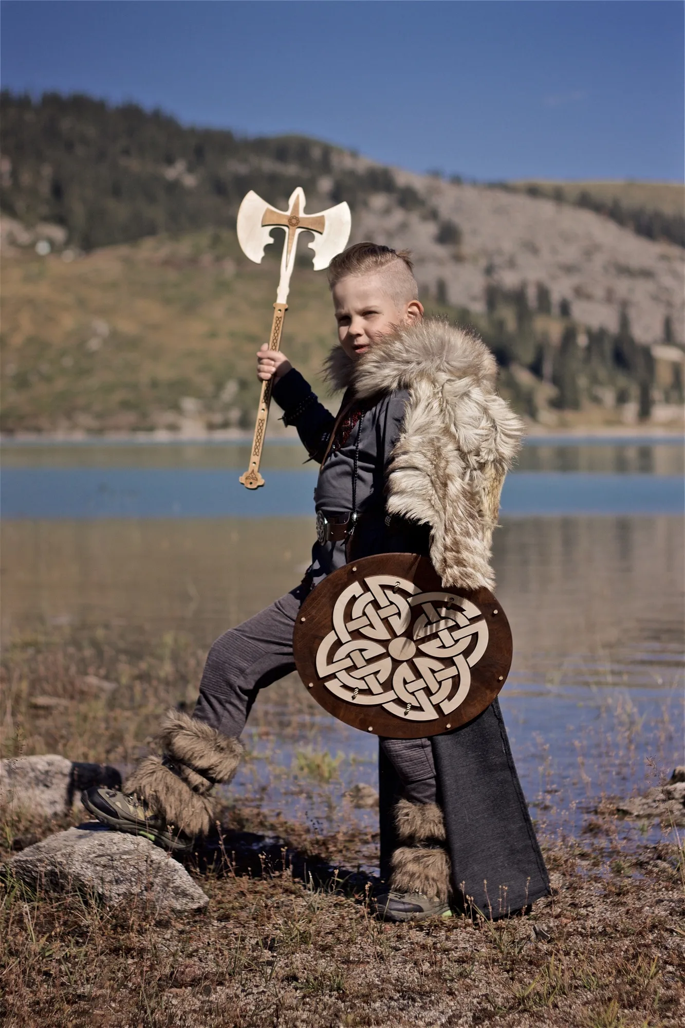 Young viking warrior in the Wolfskin cloak with wooden shield and axe